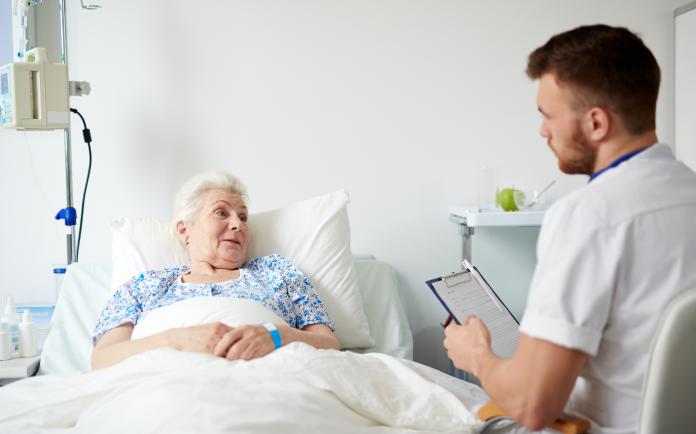 ágyban fekvő beteggel beszélget a kezelőorvosa